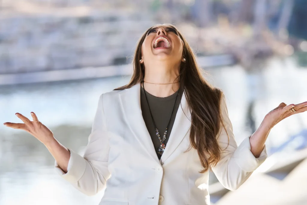 Christina in a white blazer smiling with her head back.
